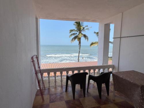 a balcony with two chairs looking out at the ocean at Kapila Beach Resort in Dapoli