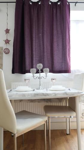 a table with two chairs and a purple curtain at Lux Apartment in Gatwick in Crawley