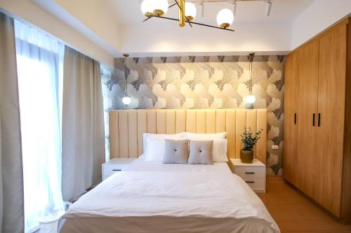 a bedroom with a large white bed and a window at Cozy & Modern 2BR Unit in Manhattan Cubao with Balcony in Sampong