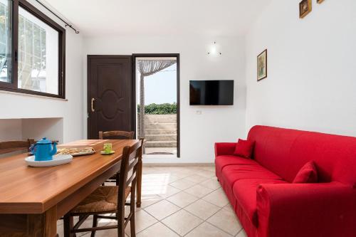 ein Wohnzimmer mit einem roten Sofa und einem Tisch in der Unterkunft Su Nidu Virde - Ginepro in Orosei