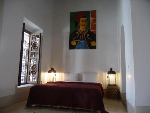 a bedroom with a bed with a painting on the wall at Riad Matham in Marrakech