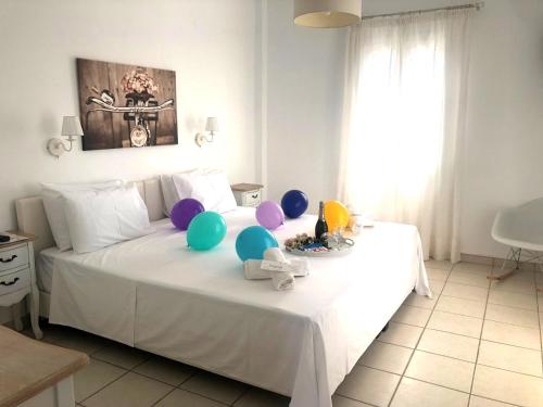 a bedroom with a white bed with balloons on it at Tzane Studios & Apartments - Steps away from Golden Beach in Chrissi Akti