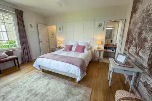 a bedroom with a large bed with pink pillows at Villa Saint-Lager - Séjour de charme au cœur du Beaujolais in Saint-Lager