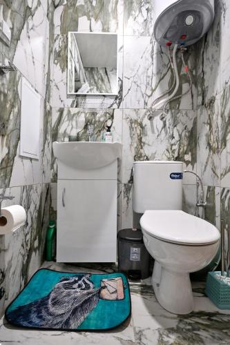a bathroom with a toilet and a floor rug at Mint Funny Condo in Varna City