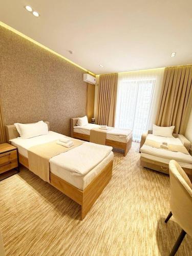 a hotel room with three beds and a window at North Star Hotel in Yakkasaray