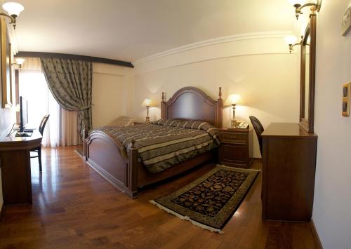 
a bedroom with a bed and a dresser at Aeton Melathron Hotel in Tríkala
