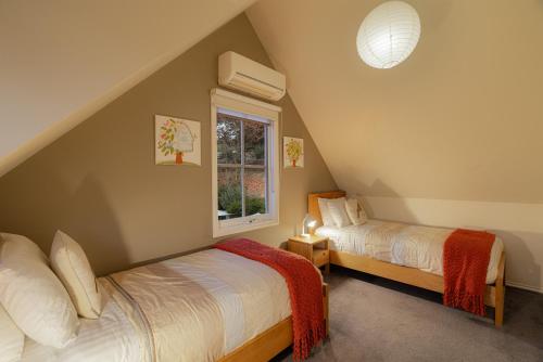 ein Schlafzimmer im Dachgeschoss mit zwei Betten und einem Fenster in der Unterkunft BlueMill Cottage in Bright