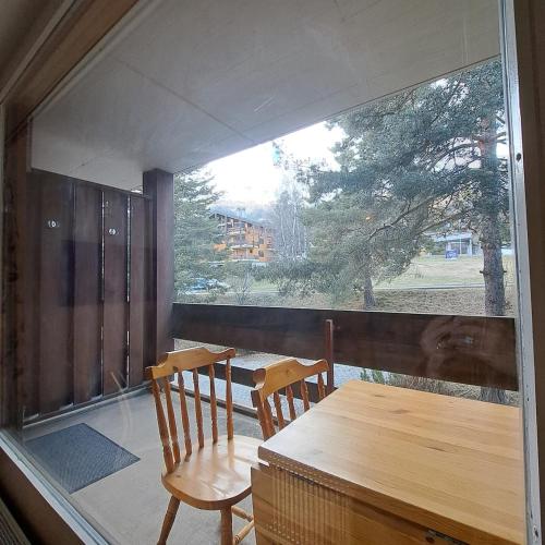 a table and two chairs on a balcony with a window at Le Flocon Studio in Ovronnaz close to the baths in Ovronnaz