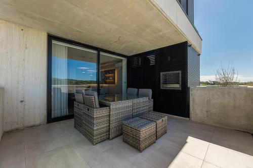 a patio with wicker chairs and a table on a balcony at GuestReady - A charming place in a private condo in Apúlia