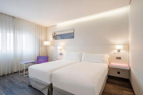 Una habitación de hotel con una cama blanca y una silla azul. en Exe Coruña, en A Coruña