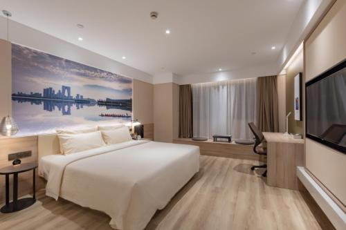 a hotel room with a bed and a flat screen tv at Atour Hotel (Suzhou Wujiang Wuyue Plaza) in Suzhou