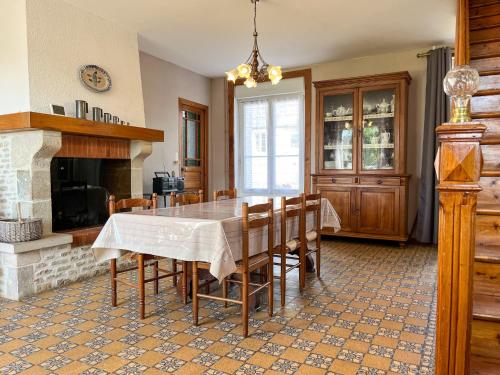 une salle à manger avec une table et des chaises et une cheminée dans l'établissement Authentique Maison au coeur de Rocheville, 