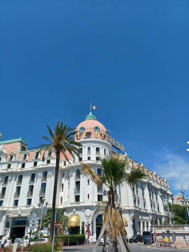 un grand bâtiment blanc avec des palmiers devant dans l'établissement Seaside place,1 min to the beach, WI FI, parking, à Nice