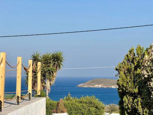 a view of the ocean through a fence with palm trees at Yaleena Residences in Drios