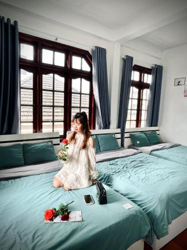 a woman sitting on a large bed with flowers at Dona Hotel in Da Lat