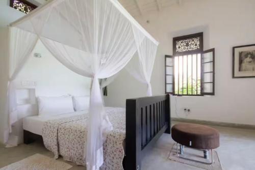 a white bedroom with a bed and a chair at Blissful Retreat in Batticaloa