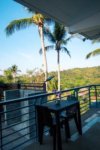 a table and chairs on a balcony with palm trees at AV Suites in Puerto Galera