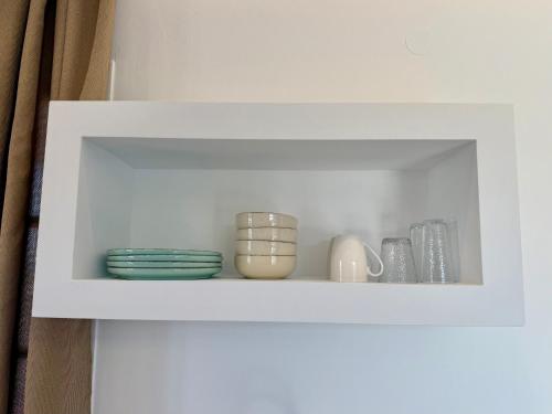a white cabinet with plates and vases on it at Yaleena Residences in Drios