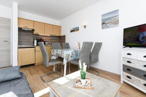 a living room with a table and a kitchen at Ferienwohnungen Haus Boje in Neuharlingersiel