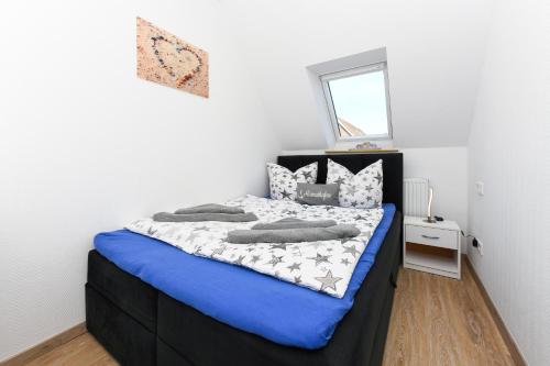 a bedroom with a bed with blue sheets and pillows at Ferienwohnungen Haus Boje in Neuharlingersiel