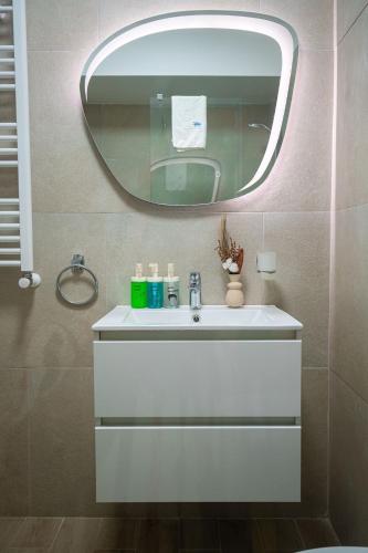 a bathroom with a white sink and a mirror at Ricky Apartment in Infinity Spa & Pool in Mamaia Sat/Năvodari