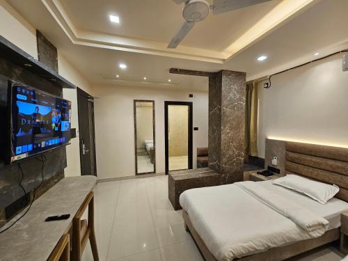 a bedroom with a bed and a flat screen tv at The Monarch Hotel By Birina in Jorhāt