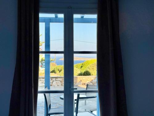 a window with two chairs looking out at the ocean at Yaleena Residences in Drios