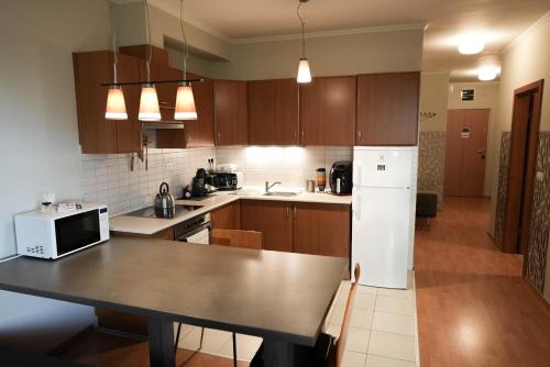 une cuisine avec une table et un réfrigérateur blanc dans l'établissement BALA Resort Apartman, à Siófok