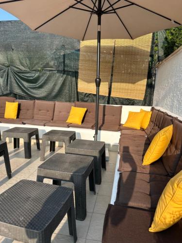 a patio with couches and tables and an umbrella at Riviera Blagaj in Blagaj