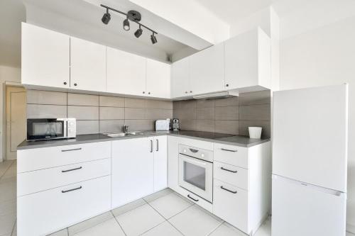 une cuisine blanche avec des armoires blanches et un micro-ondes dans l'établissement T3 avec balcon proche de La Place Castellane, à Marseille