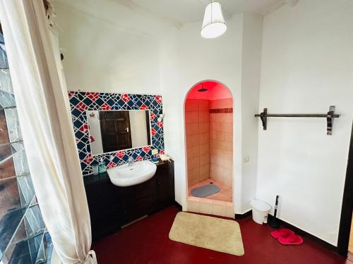 a bathroom with a sink and a shower with a mirror at Studio Cecile in Malindi