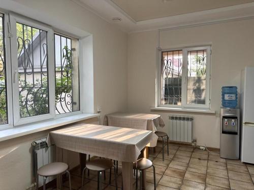 pokój z dwoma stołami i krzesłami oraz oknami w obiekcie Hostel 53 w mieście Biszkek