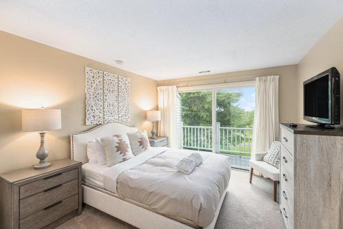 a bedroom with a bed and a tv and a window at Beautiful Comfy 2 Bedroom Condo Stunning Golf Course Views 5166 in Traverse City