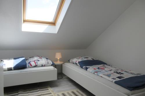 a white room with a bed with a window and a lamp at Beachhouse in Langeoog