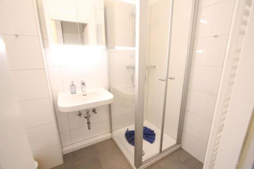 a white bathroom with a sink and a shower at Beachhouse in Langeoog