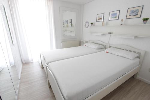 two beds in a white bedroom with white walls at Blaue Dören in Langeoog