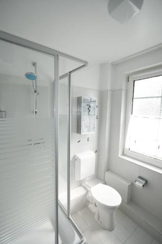 a white bathroom with a toilet and a shower at Austernfischerin in Langeoog