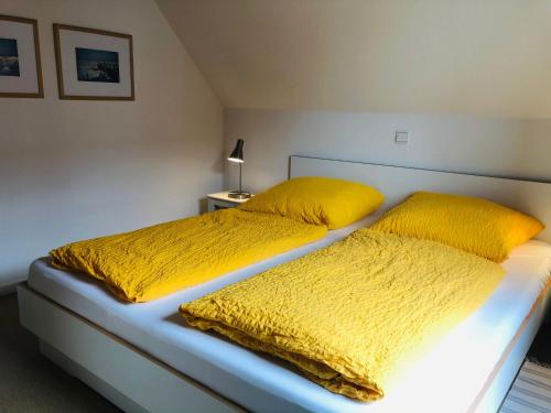 Un dormitorio con dos camas con almohadas amarillas. en Am Wall 16 - Ferienhaus, en Langeoog