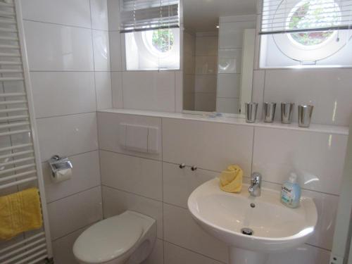 Un baño blanco con inodoro y lavabo. en Am Wall 16 - Ferienhaus, en Langeoog