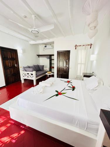 a bedroom with a large white bed with a clock on it at Studio Cecile in Malindi