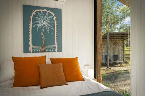 a bedroom with a bed with a palm tree picture on the wall at Rosemont by Tiny Away in Kempsey