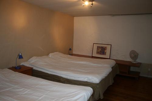 two beds in a hotel room with white sheets at Visby Innerstad Lägenheter & Rum in Visby