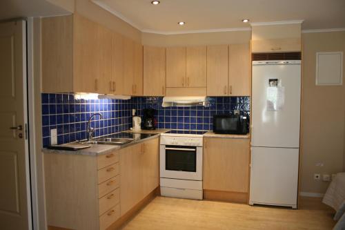 a kitchen with wooden cabinets and a white refrigerator at Visby Innerstad Lägenheter & Rum in Visby