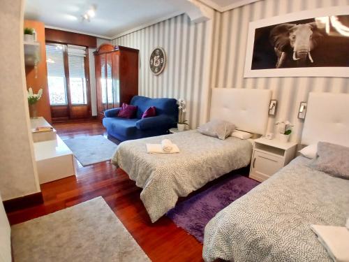 a bedroom with two beds and a blue couch at mariajesus etxea in Bermeo