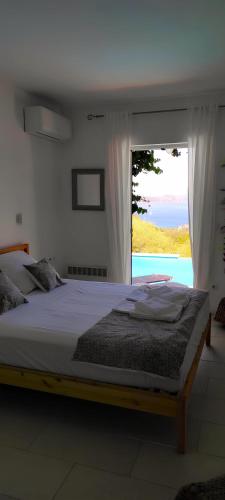 a bedroom with a large bed with a large window at villa Séléné in Sivota
