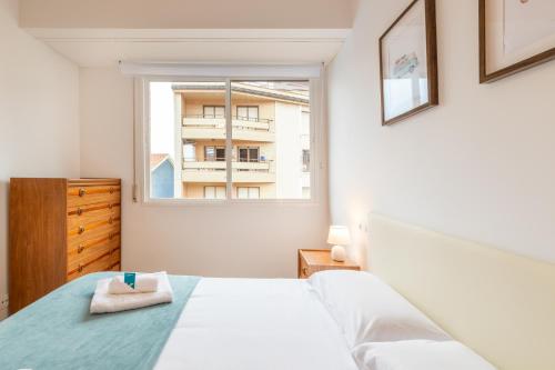 a white bedroom with a bed and a window at Eguzkilore - baskeyrentals in Lekeitio