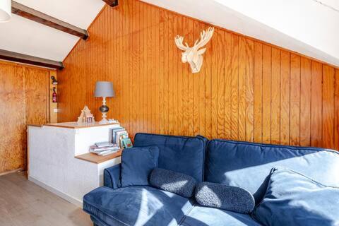 - un salon avec un canapé bleu et un mur en bois dans l'établissement vue du Lac, aux Angles
