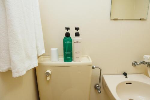 a bathroom with two bottles on top of a toilet at ビジネスホテル寿屋 in Handa