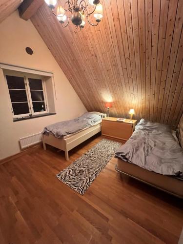 two beds in a room with a wooden ceiling at Half-timbered house in Österlen in Sjöbo