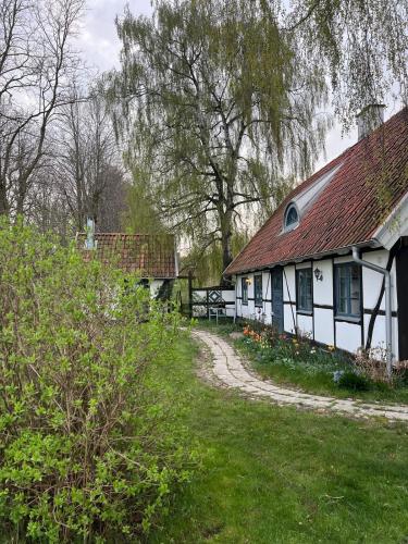 a white house with a red roof and a grass yard at Half-timbered house in Österlen in Sjöbo